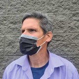 adult male wearing black color usa made surgical mask head tilted left to show side of the mask